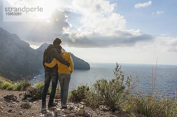 Rückenansicht eines Paares  das Arm in Arm steht und aufs Meer blickt  Mallorca  Spanien