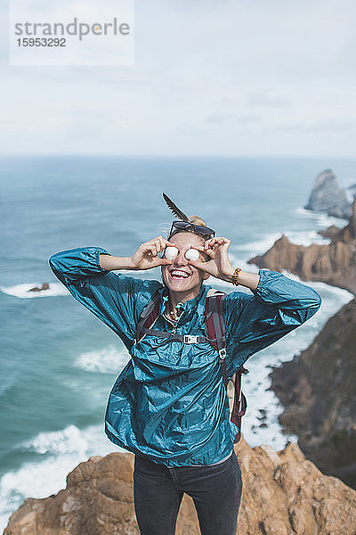 Portugal  Bezirk Lissabon  Sintra  Porträt einer Wanderin  die lächelt  während sie vorgibt  Steine als Sonnenbrille zu tragen
