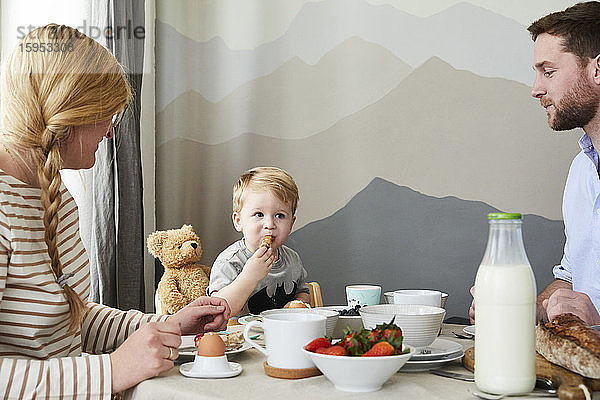 Porträt eines kleinen Jungen beim Frühstück mit seinen Eltern zu Hause