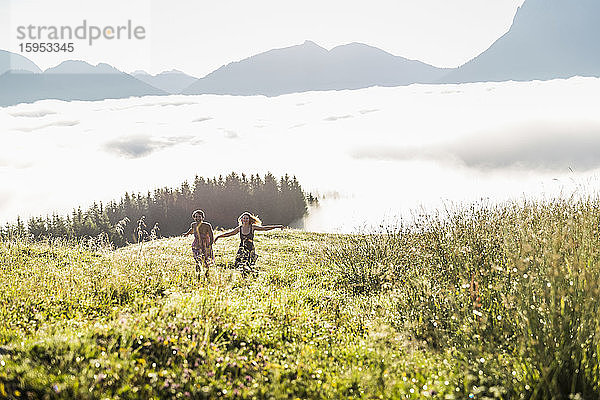 Zwei Freundinnen laufen auf einer Wiese in den Bergen  Achenkirch  Österreich