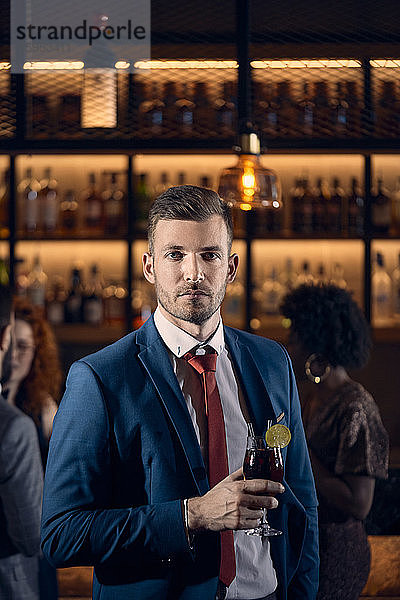 Porträt eines seriösen jungen Mannes bei einem Cocktail in einer Bar