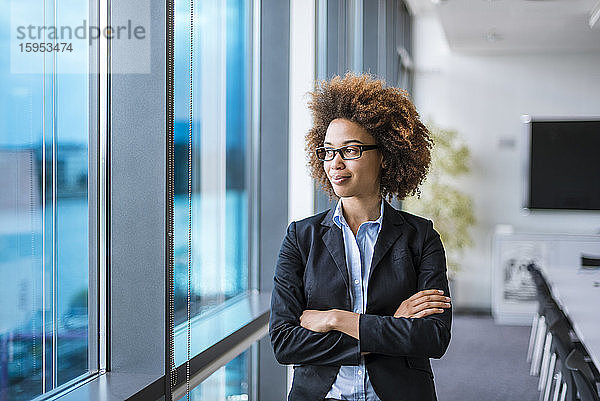 Porträt einer selbstbewussten jungen Geschäftsfrau im Konferenzraum  die aus dem Fenster schaut