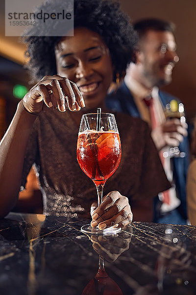 Glückliche Frau bei einem Cocktail in einer Bar