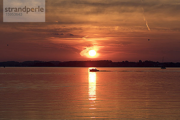 Deutschland  Bayern  Chiemsee  Silhouette eines einsamen Motorbootes  das bei stimmungsvollem Sonnenuntergang segelt