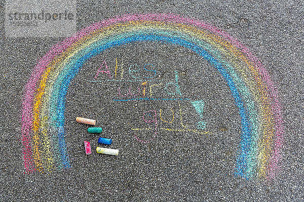 Gemalter Regenbogen auf der Straße mit dem Text 'Alles wird sich fügen'.