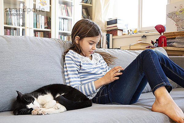 Mädchen sitzt auf dem Sofa und benutzt ein digitales Tablett