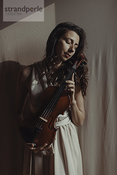 Frau hält Geige mit geschlossenen Augen