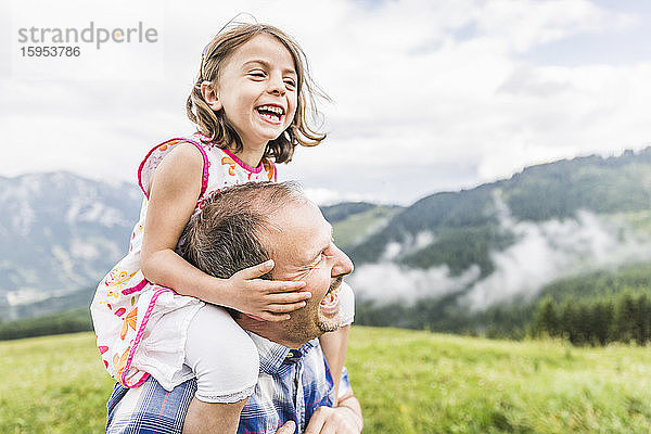 Glücklicher Vater trägt Tochter auf den Schultern auf einer Wiese in den Bergen  Achenkirch  Österreich