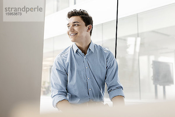 Porträt eines lächelnden jungen Geschäftsmannes am Fenster im Büro