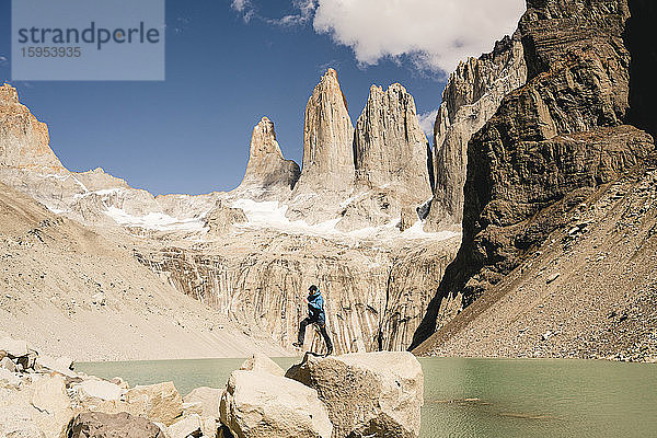Wanderer springt in der Berglandschaft am Seeufer am Mirador Las Torres im Nationalpark Torres del Paine  Patagonien  Chile