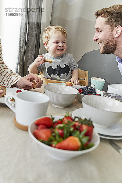 Porträt eines glücklichen kleinen Jungen  der sich mit seinem Vater am Frühstückstisch vergnügt