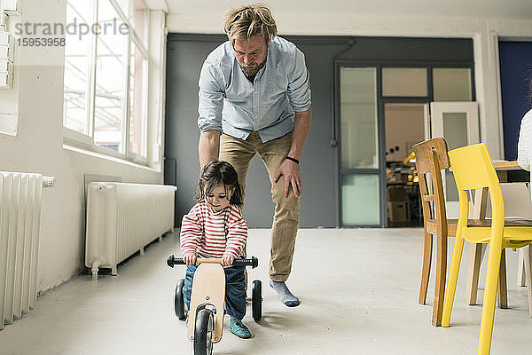 Vater beobachtet Tochter mit Balance-Fahrrad