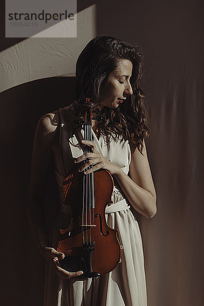 Frau hält Geige mit geschlossenen Augen