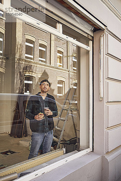 Mann renoviert Ladenstandort  trinkt Kaffee  schaut aus dem Fenster