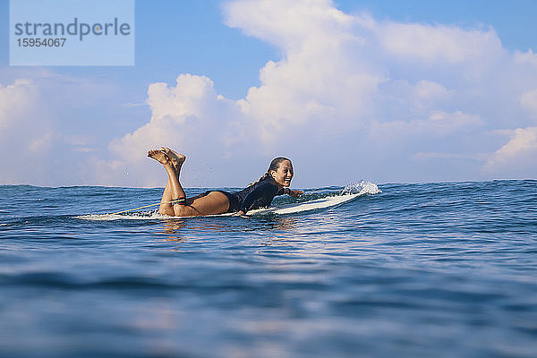 Glückliche Frau liegt auf einem Surfbrett im Meer  Bali  Indonesien