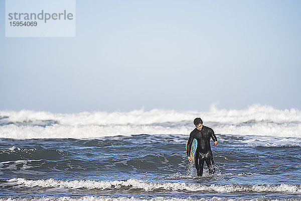 Behinderter Surfer mit Surfbrett am Strand