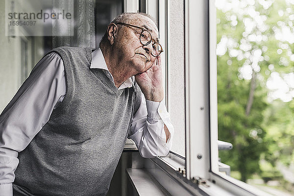 Porträt eines traurigen älteren Mannes  der aus dem Fenster schaut