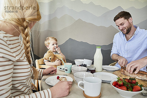 Porträt eines kleinen Jungen  der mit seinen Eltern am Frühstückstisch sitzt