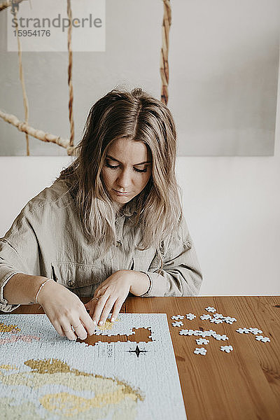 Frau spielt während der Hausquarantäne mit Puzzle am Tisch