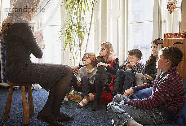 Kinder in einem Klassenzimmer während der Erzählstunde mit dem Lehrer