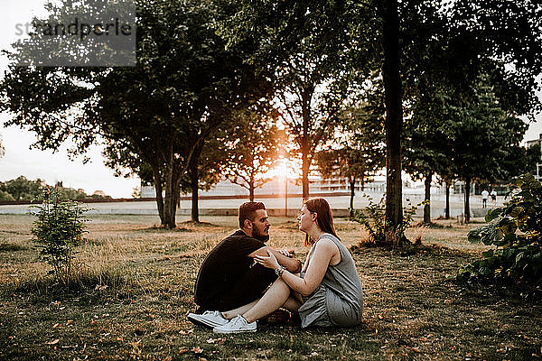Junges Paar sitzt bei Sonnenuntergang in einem Park