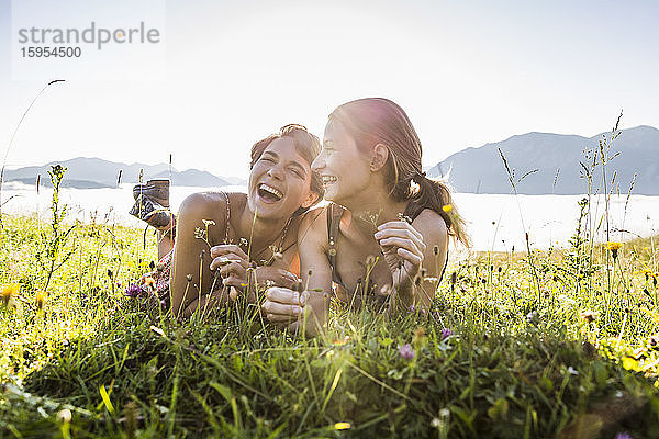 Zwei glückliche Freundinnen liegen auf einer Wiese in den Bergen  Achenkirch  Österreich