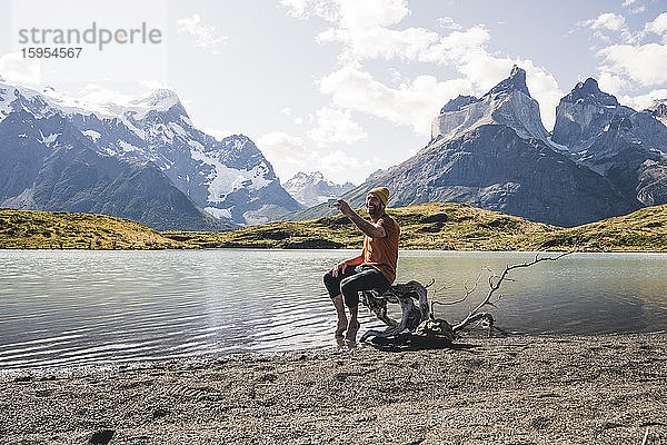 Glücklicher Mann bei einem Selbstversuch in einer Berglandschaft am Seeufer im Nationalpark Torres del Paine  Patagonien  Chile