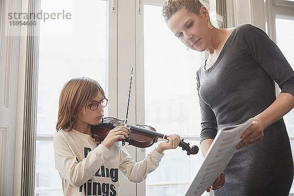 Lehrer unterrichtet einen Jungen  der während einer Unterrichtsstunde Geige spielt