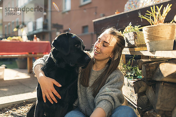 Glückliche junge Frau mit Hund im Garten