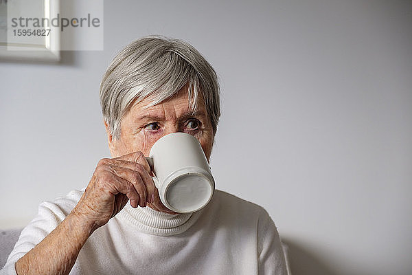 Porträt einer älteren Frau  die zu Hause Tee trinkt