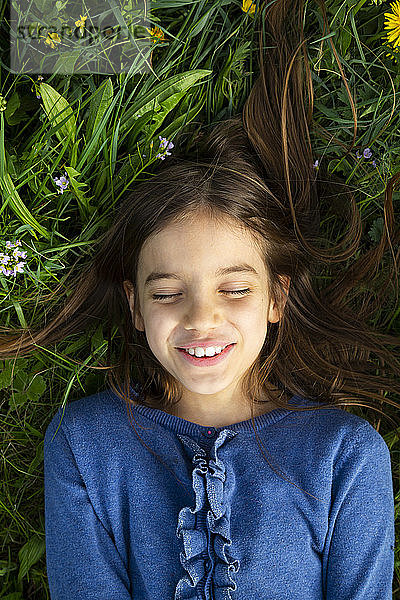 Porträt eines Mädchens mit geschlossenen Augen  das sich im Frühling auf einer Wiese entspannt