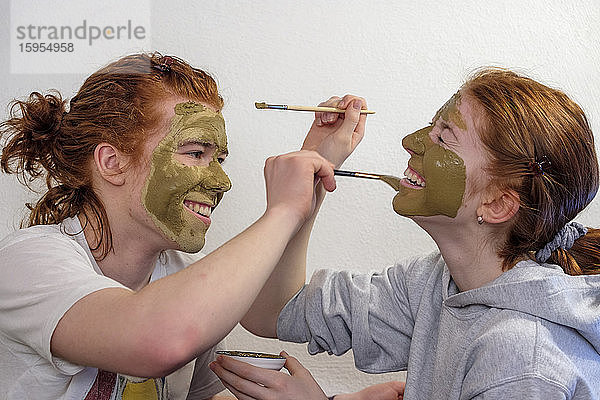 Bruder und Schwester amüsieren sich beim Anlegen der Gesichtsmaske