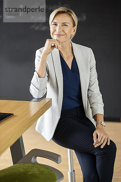 Porträt einer selbstbewussten blonden Geschäftsfrau im Konferenzraum mit Tafel