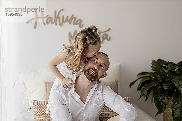 Kleines Mädchen küsst zu Hause ihren Vater