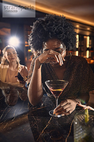 Fröhliche Frau trinkt einen Cocktail in einer Bar