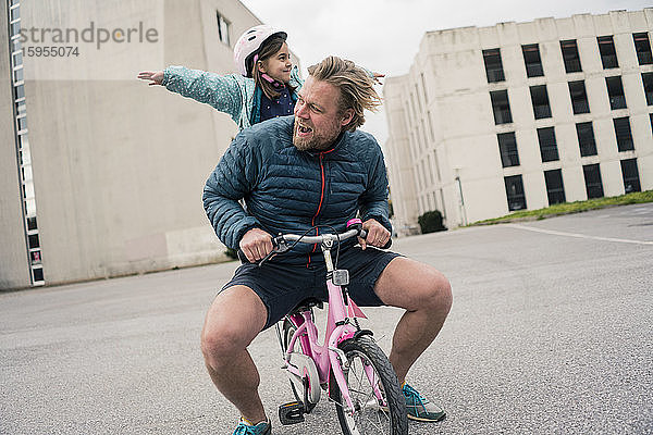 Verspielter Vater mit Tochter auf dem Fahrrad