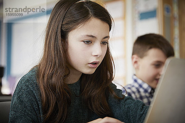 Mädchen und Junge in einem Klassenzimmer während einer Unterrichtsstunde über Laptops