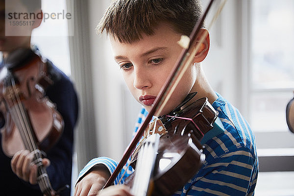 Junge spielt Geige während einer Unterrichtsstunde