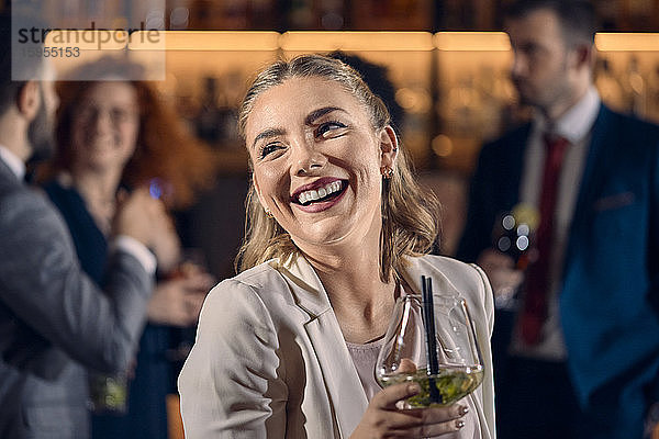 Porträt einer glücklichen jungen Frau bei einem Cocktail in einer Bar