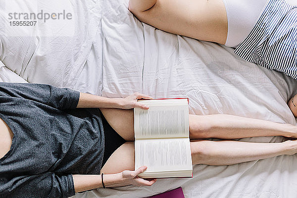Ernten von zwei Frauen in Unterwäsche  die mit einem Buch auf dem Bett liegen
