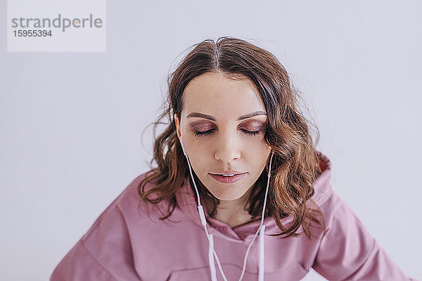 Frau mit geschlossenen Augen  die über Kopfhörer Musik hört