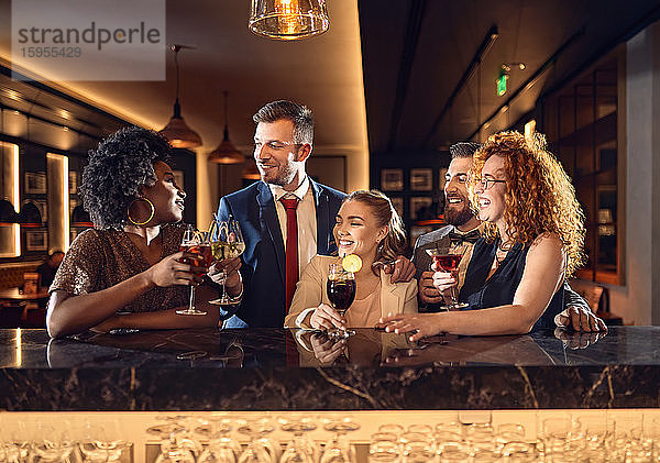 Fröhliche Freunde beim geselligen Beisammensein in einer Bar mit Cocktails