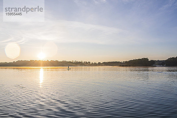 Frau steht morgens auf einem See an Bord  Deutschland