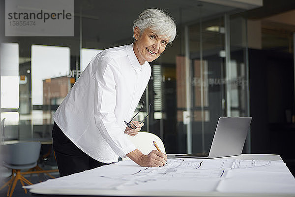 Porträt eines Architekten  der im Büro am Bauplan arbeitet