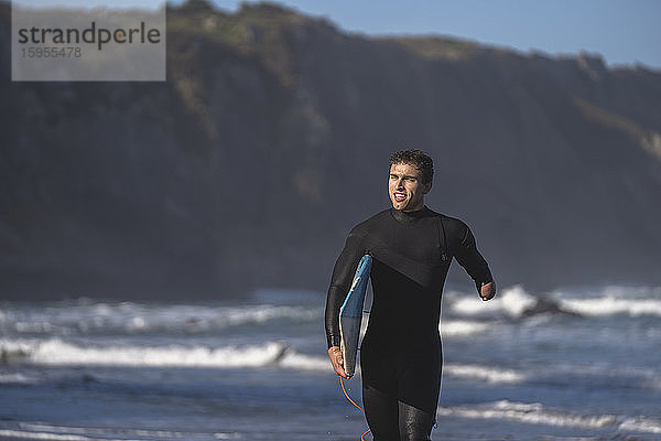 Behinderter Surfer mit Surfbrett am Strand