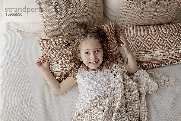 Porträt eines glücklichen kleinen Mädchens auf dem Bett liegend