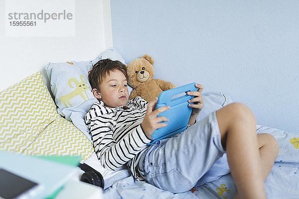 Im Bett liegender Junge mit digitalem Tablett