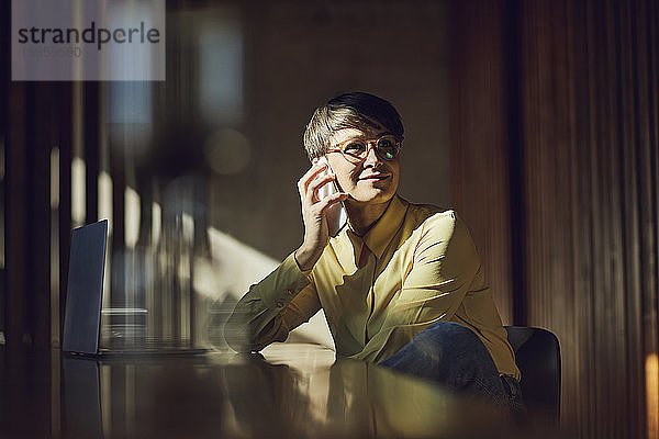 Geschäftsfrau sitzt in ihrem nachhaltigen Büro und telefoniert