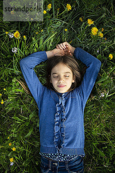 Porträt eines Mädchens mit geschlossenen Augen  das sich im Frühling auf einer Wiese entspannt