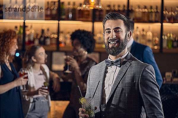 Porträt eines glücklichen jungen Mannes bei einem Cocktail in einer Bar